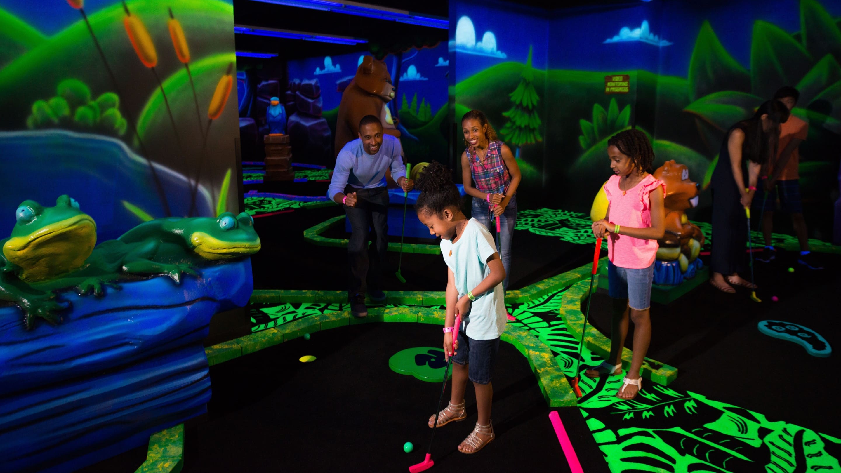 Family playing glow-in-the-dark mini golf