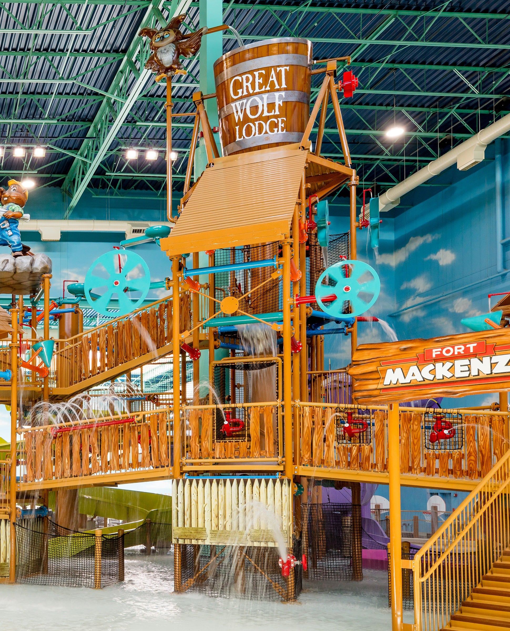 Indoor water park at Great Wolf Lodge featuring a wooden splash tower with a large tipping bucket and water slides, labeled "Fort Mackenzie."