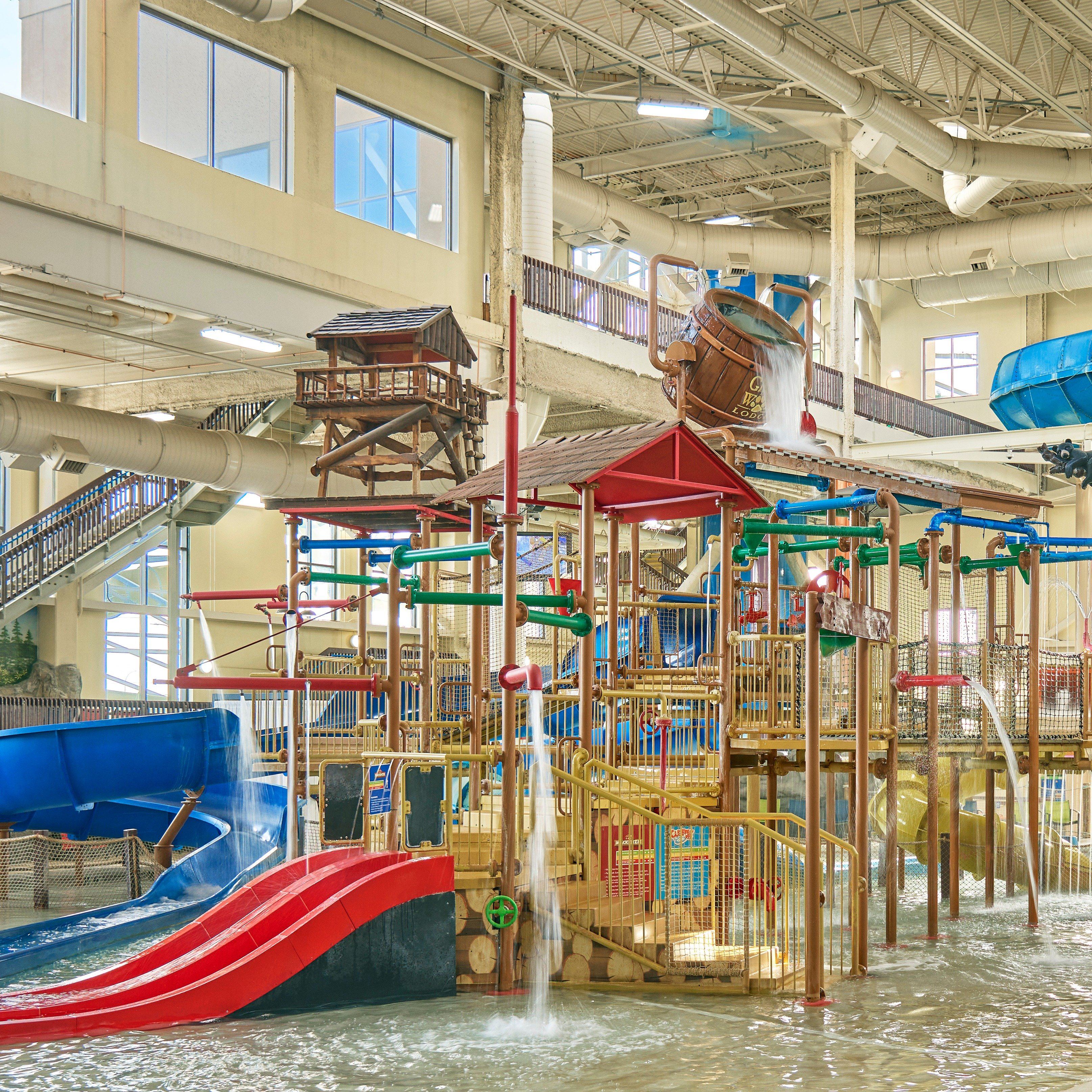 Indoor water park with multiple colorful slides, water features, and play structures surrounded by a spacious, well-lit environment.